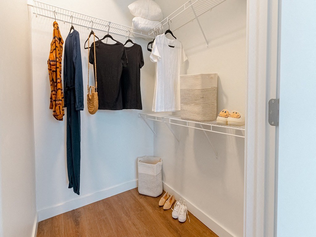 a closet with clothes and shoes in it and a rack with clothes on it